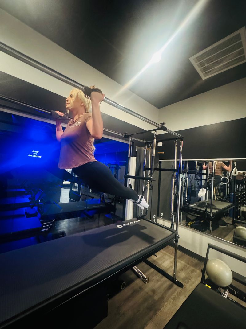 Pilates Tower hanging exercise during private training at Core Ambitions