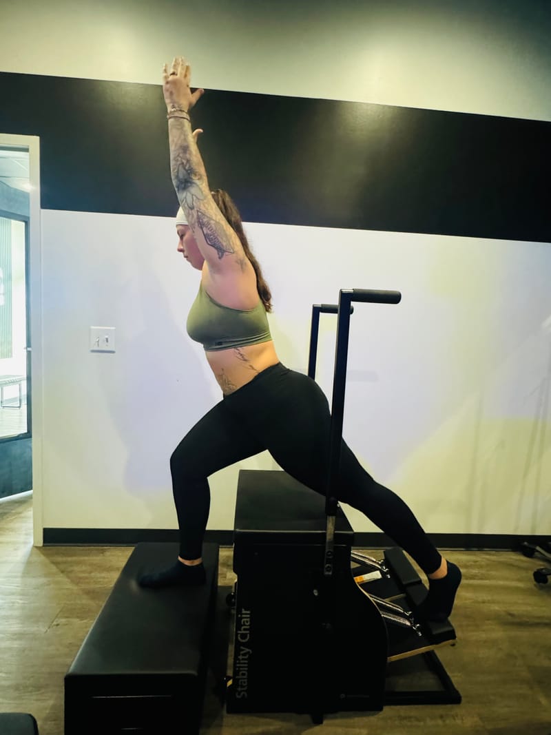 Standing lunge with overhead reach on the Stability Chair at Core Ambitions